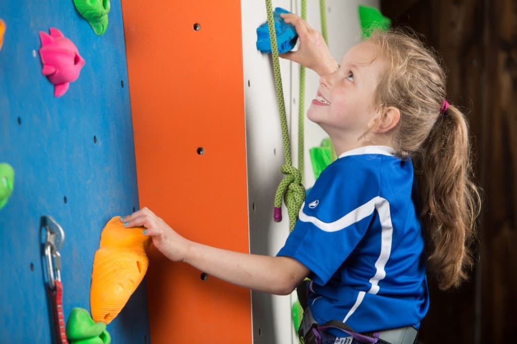 Kind beim Klettern an der bunten Kletterwand